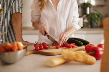 woman cutting tomatoes in white button up 