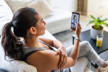 Woman calling a doctor after suffering an injury during a home workout stock photo