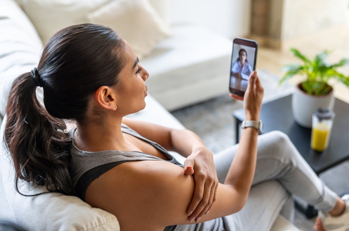 Woman calling a doctor after suffering an injury during a home workout stock photo