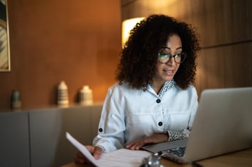 Woman sitting at table using laptop for video telemedicine