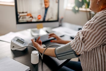 Patient using an at home blood pressure monitor during a virtual doctor visit