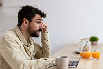 Man sitting at table uising laptop to speak with docotr on a telemedicine video call