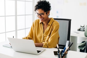 Young adult woman sitting at desk using laptop on video call