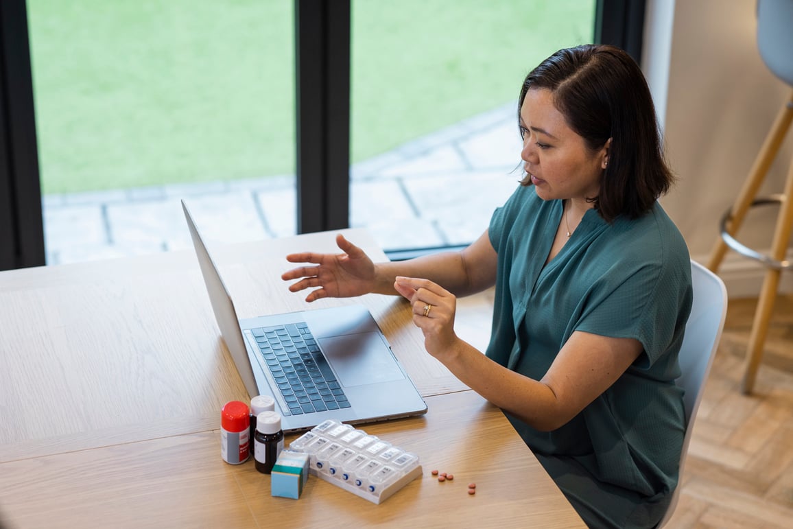 Female patient sitting at table using a tablet for a video telemedicine call with her doctor to ask about her prescriptions