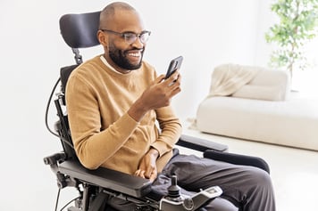 Man in wheelchair using cell phone video call for telemedicine appointment